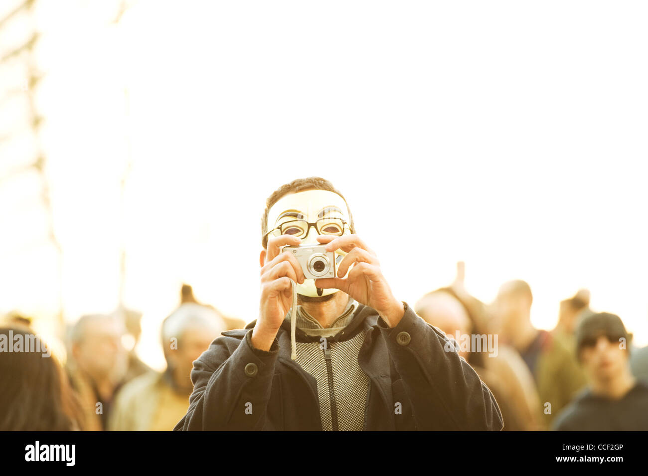 A guy with a Vendetta mask taking a photo at the demonstration in Lisbon Stock Photo