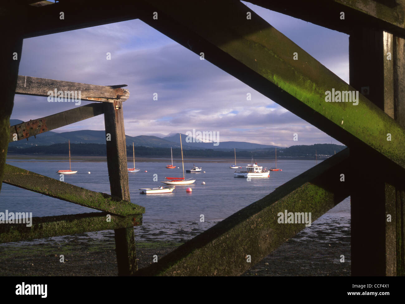 Boats on Menai Strait with Snowdonia in background viewed from beneath Beaumaris Pier Anglesey North Wales UK Stock Photo