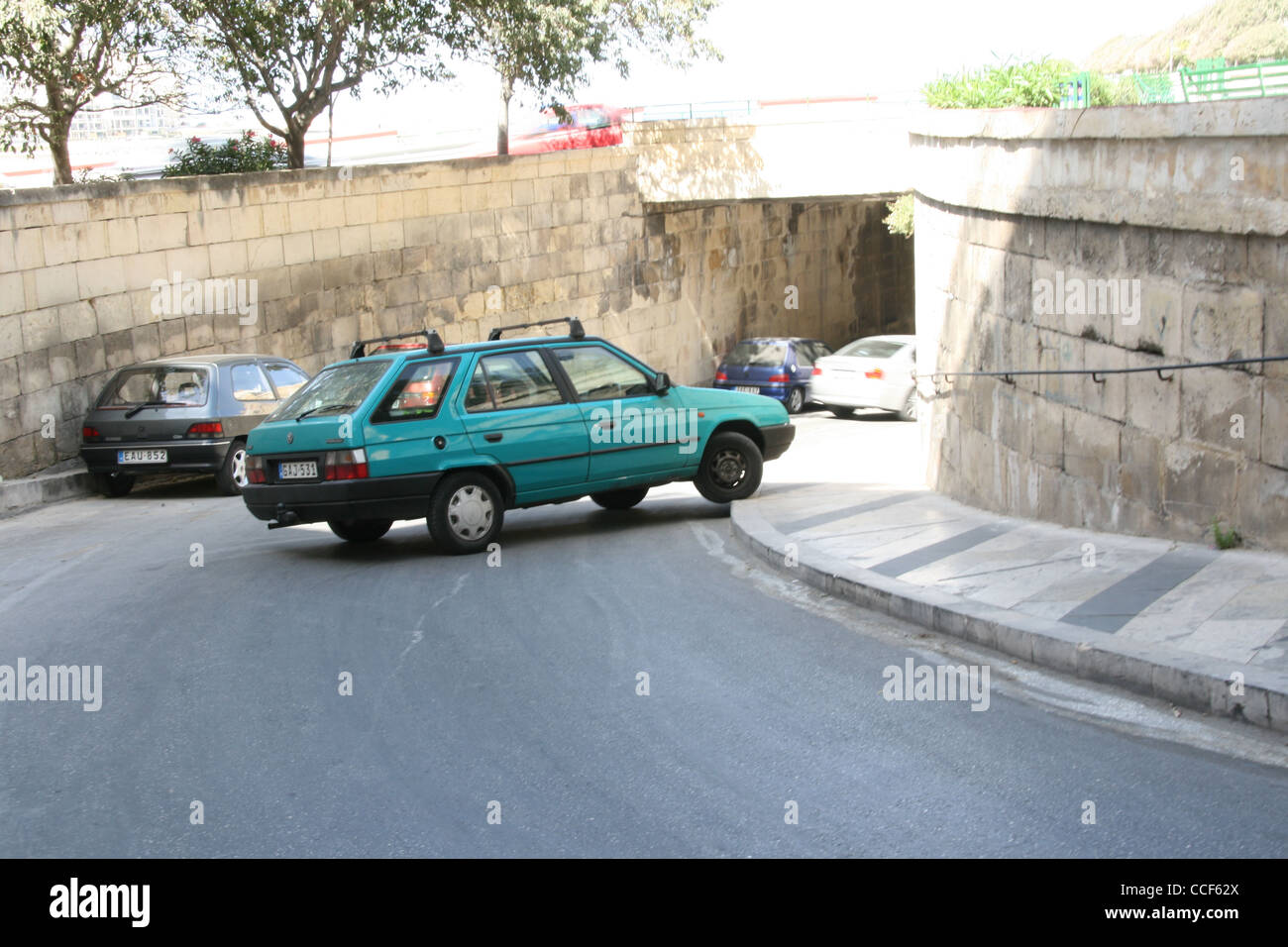 A car stopped across the road and pavementnear the underpass to where the the Sliema ferry docks in Valletta. Stock Photo
