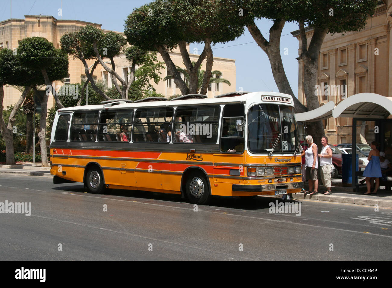 Traditional yellow and orange bus on the street of Mosta in Malta. Stock Photo