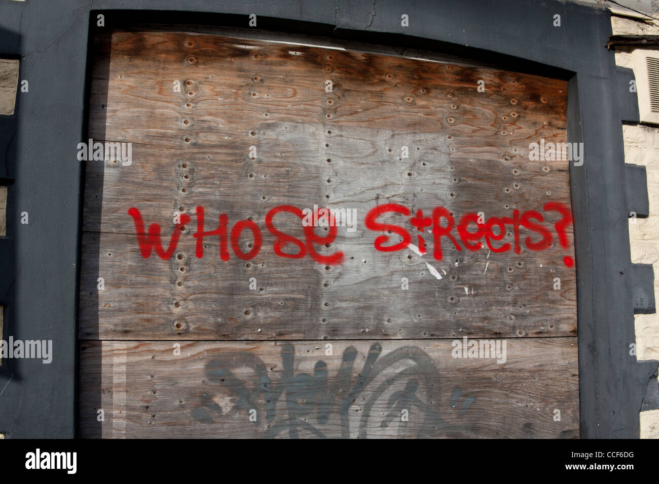 'Whose Streets?' graffiti on boarded up building Cardiff South Wales UK Stock Photo