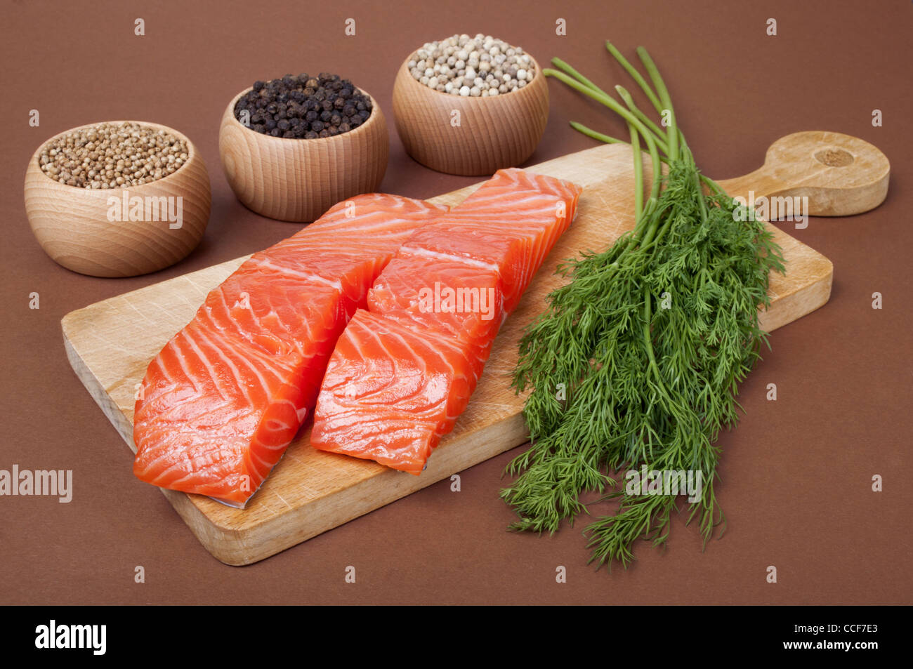 Still life with two slices trout fillet and spices on brown background Stock Photo