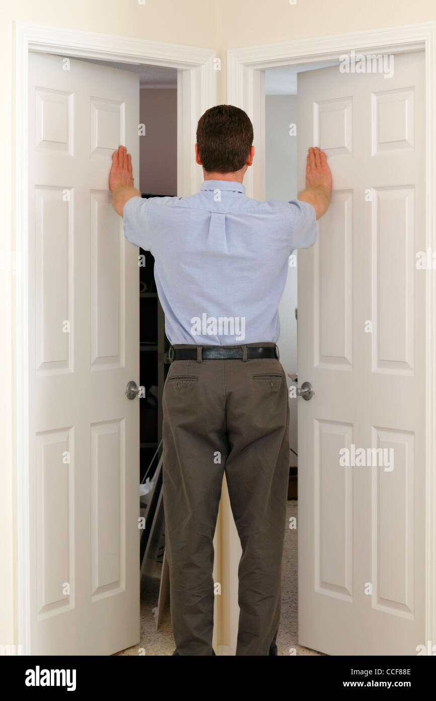 Indecision shows a man opening two doors. Man in the middle of two doors pushes open both at the same time and needs to choose which to walk through. Stock Photo