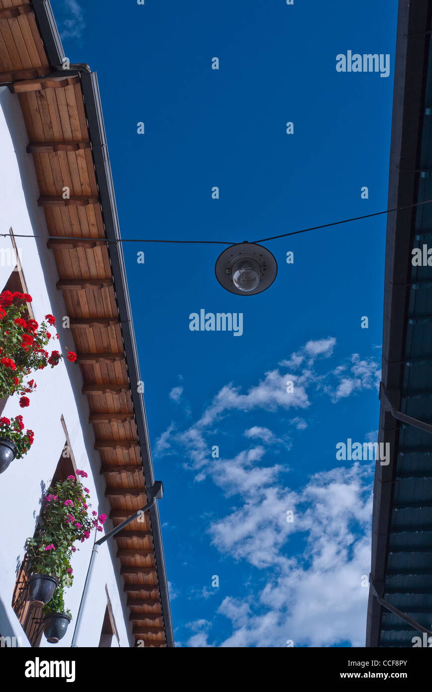 A view looking up at the roof eaves, window box flowers and blue sky at Calle La Ronda, the oldest street in Quito, Ecuador. Stock Photo