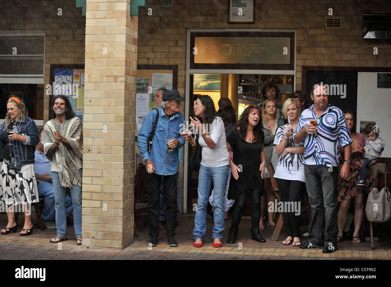 People listen to music during a heavy shower of rain at The Brunswick Heads hotel in Northern NSW Stock Photo
