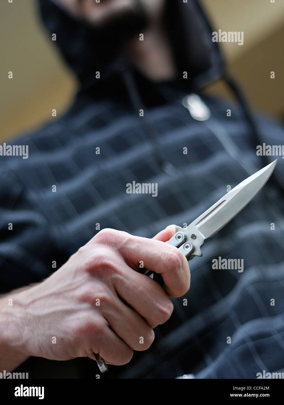 Knife Crime. Hooded Male Brandishing a Butterfly Knife. Stock Photo