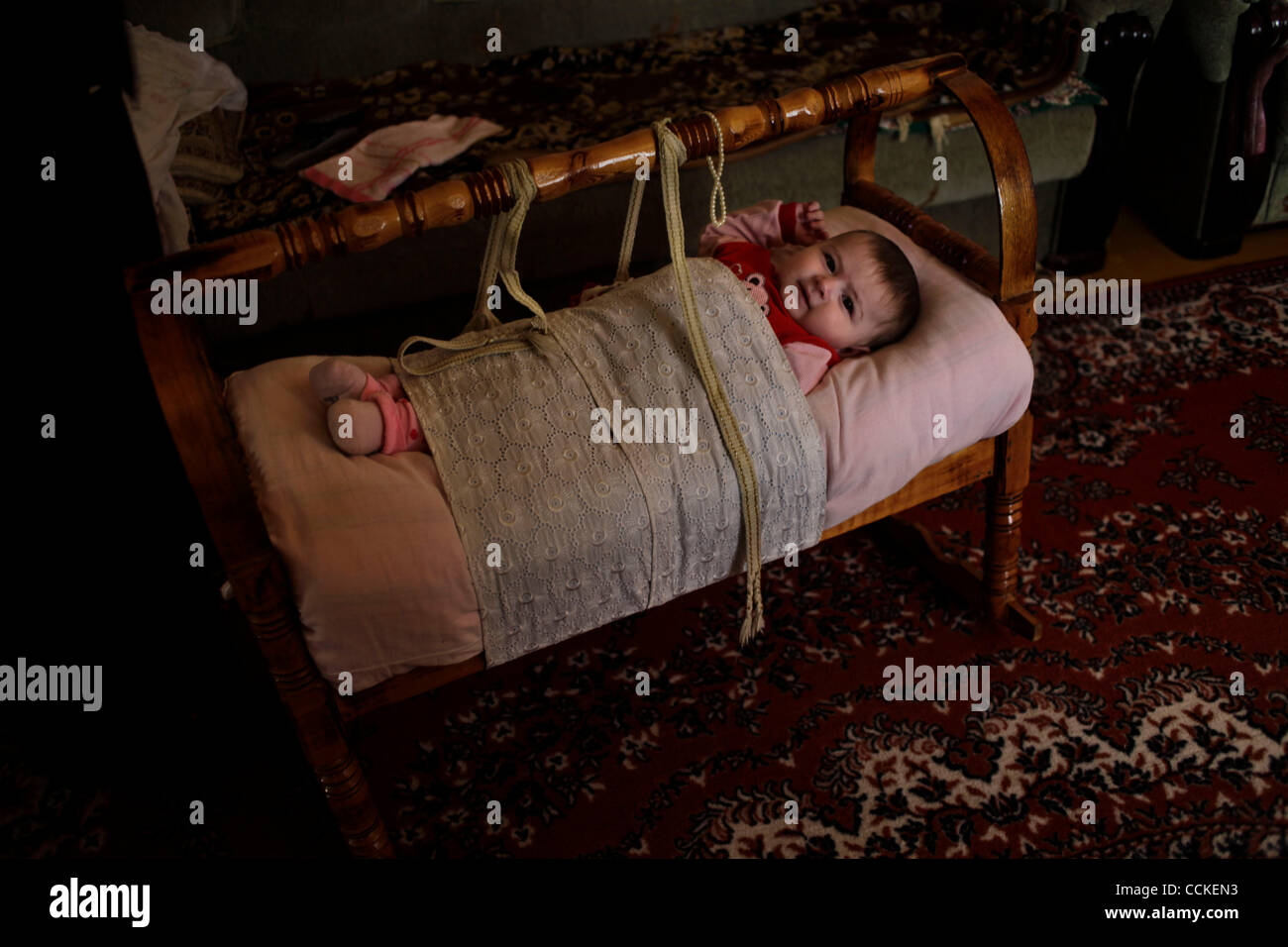 Nov 24, 2010 - Dagestan, Russia - A Dagestani baby, who is now considered an orphan after her father was killed, rests in traditional Dagestani baby bed, known as an 'aga.'  The Republic of Dagestan is a federal subject of Russia, located in the North Caucasus region. It has been a scene of low-leve Stock Photo