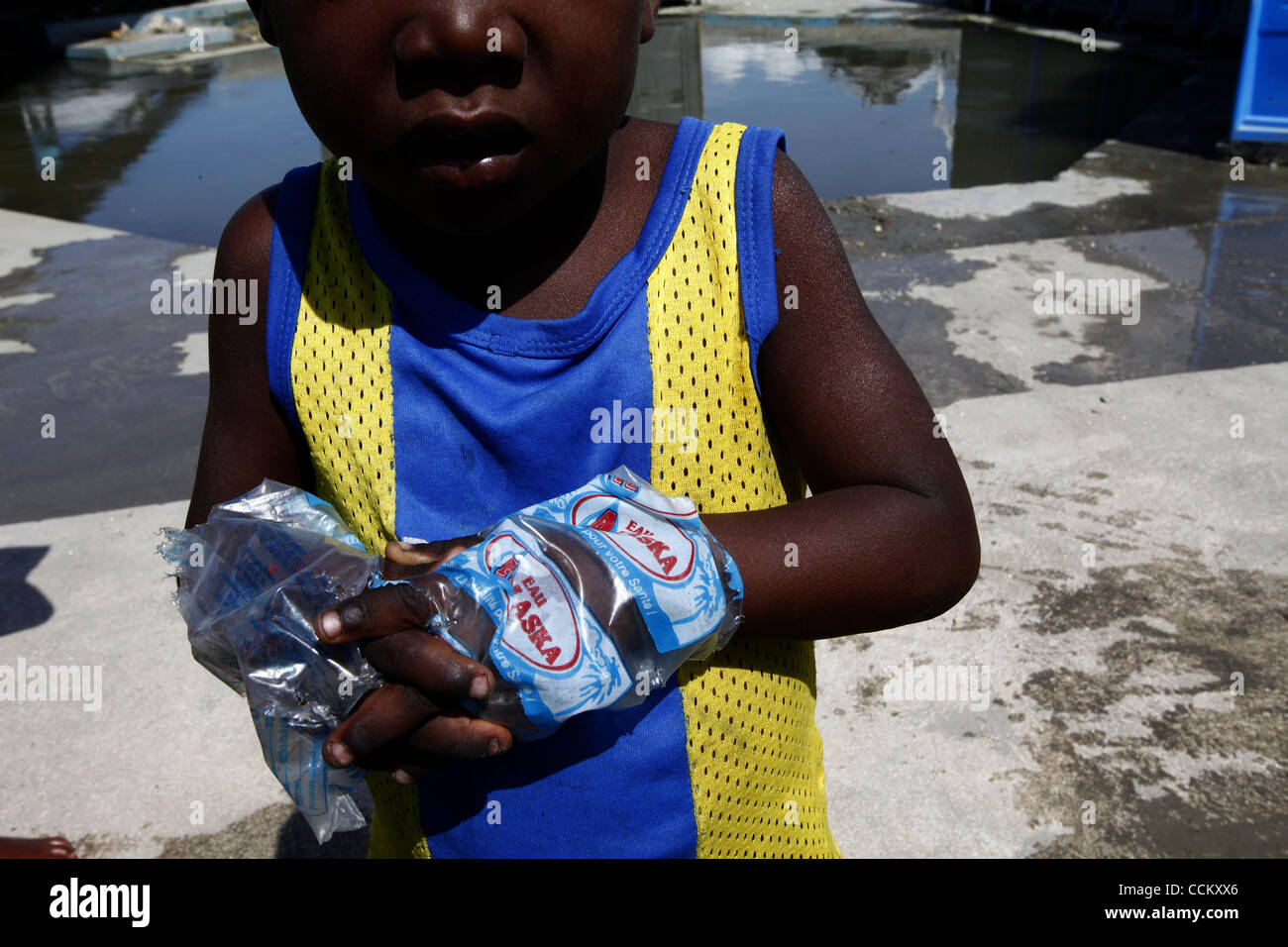 Nov 10, 2010 - Port-au-Prince, Haiti.A young resident of a tent city in the Cite Soleil area of Port-au-Prince, Haiti wears water bags as gloves in an effort, his older sisiter said, to avoid getting cholera, as other residents gather water from pipes just yards from portable toilets and flood water Stock Photo