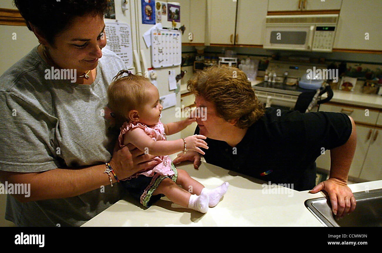 063004 sc gayrights2/2 - BOYNTON BEACH - Melanie Connolly (cq), left, holds her 7 month-old daughter, Madison Skye (cq cq cq), as her partner Maureen Connolly (cq), right, gets her nose squeezed during after-dinner cleanup Wednesday, June 30, 2004 in their Boynton Beach home. The Connollys are one o Stock Photo