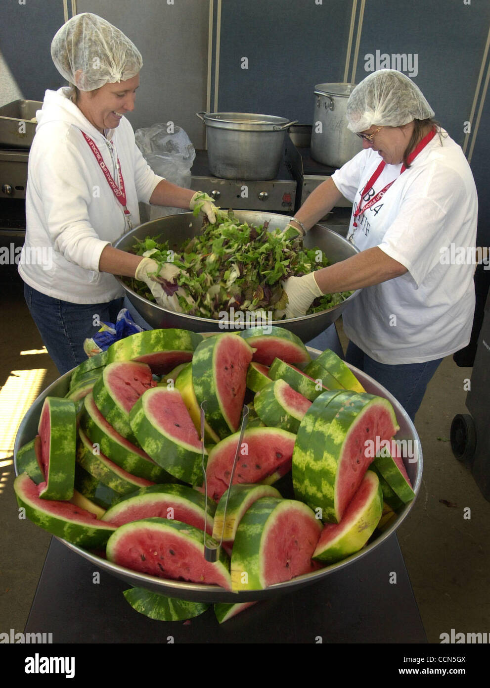 Lunch volunteers Christen Rodriguez of San Ramon, left, and Sue Beals of Hollister toss the mixed greens salad in preparation for the mid-day meal during East Bay Stand Down at Camp Parks, Saturday, August 14, 2004, in Dublin, Calif. Homeless veterans also had chili, barbecued chicken, bread and wat Stock Photo