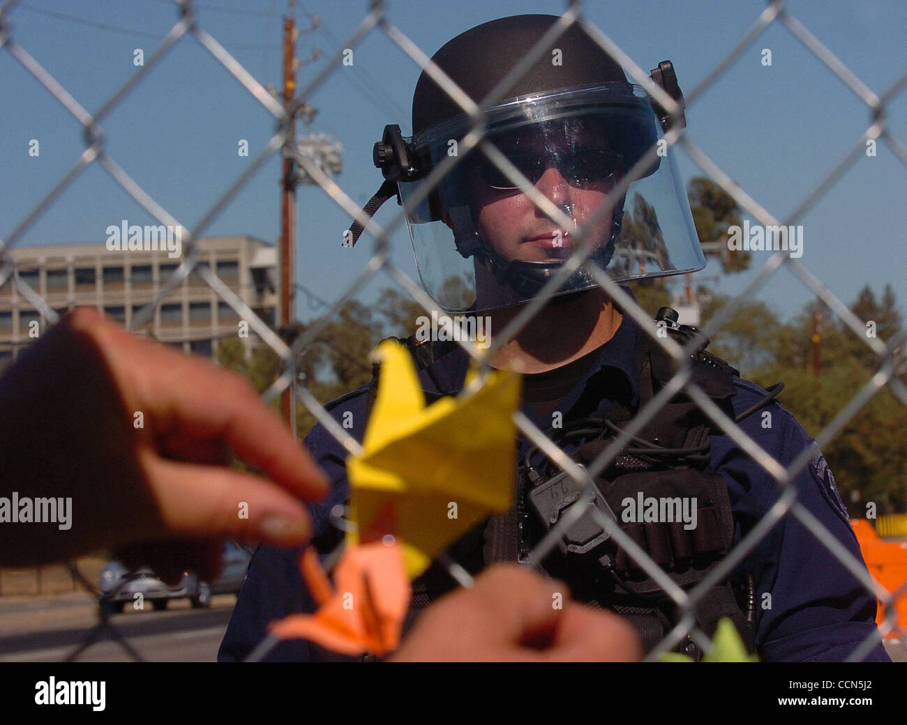 A protestor places a peace crane on a chain link fence at the entrance of the Lawrence Livermore National Labratory as police guard the gate on Sunday, August 8, 2004 in Livermore, Calif. The march was held in commemoration of the 59th anniversary of the Hiroshima and Nagasaki atomic bombings. (Jose Stock Photo