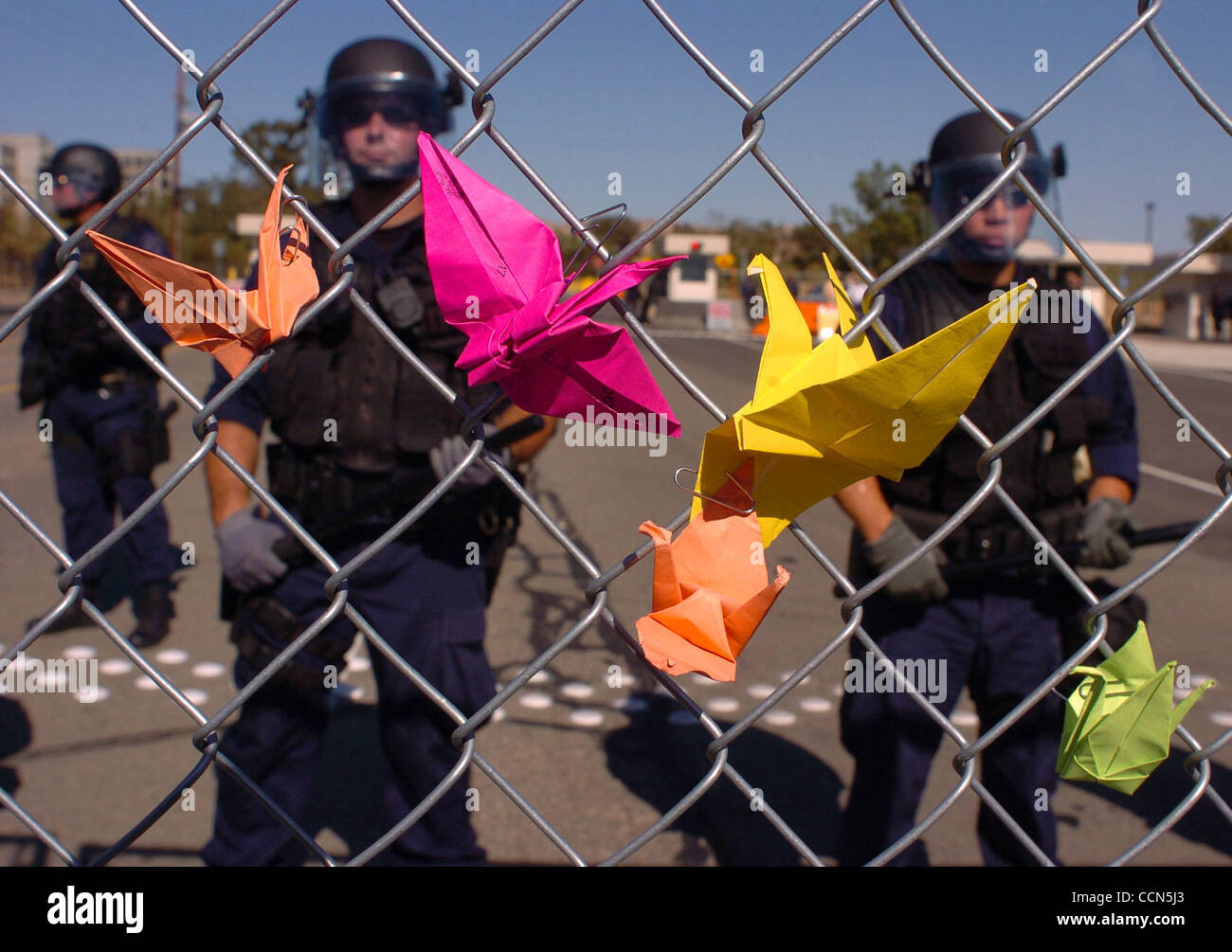 Peace cranes left by protestors on a chain link fence at the entrance of the Lawrence Livermore National Labratory as police stand guard on Sunday, August 8, 2004 in Livermore, Calif. The march was held in commemoration of the 59th anniversary of the Hiroshima and Nagasaki atomic bombings. (Jose Car Stock Photo