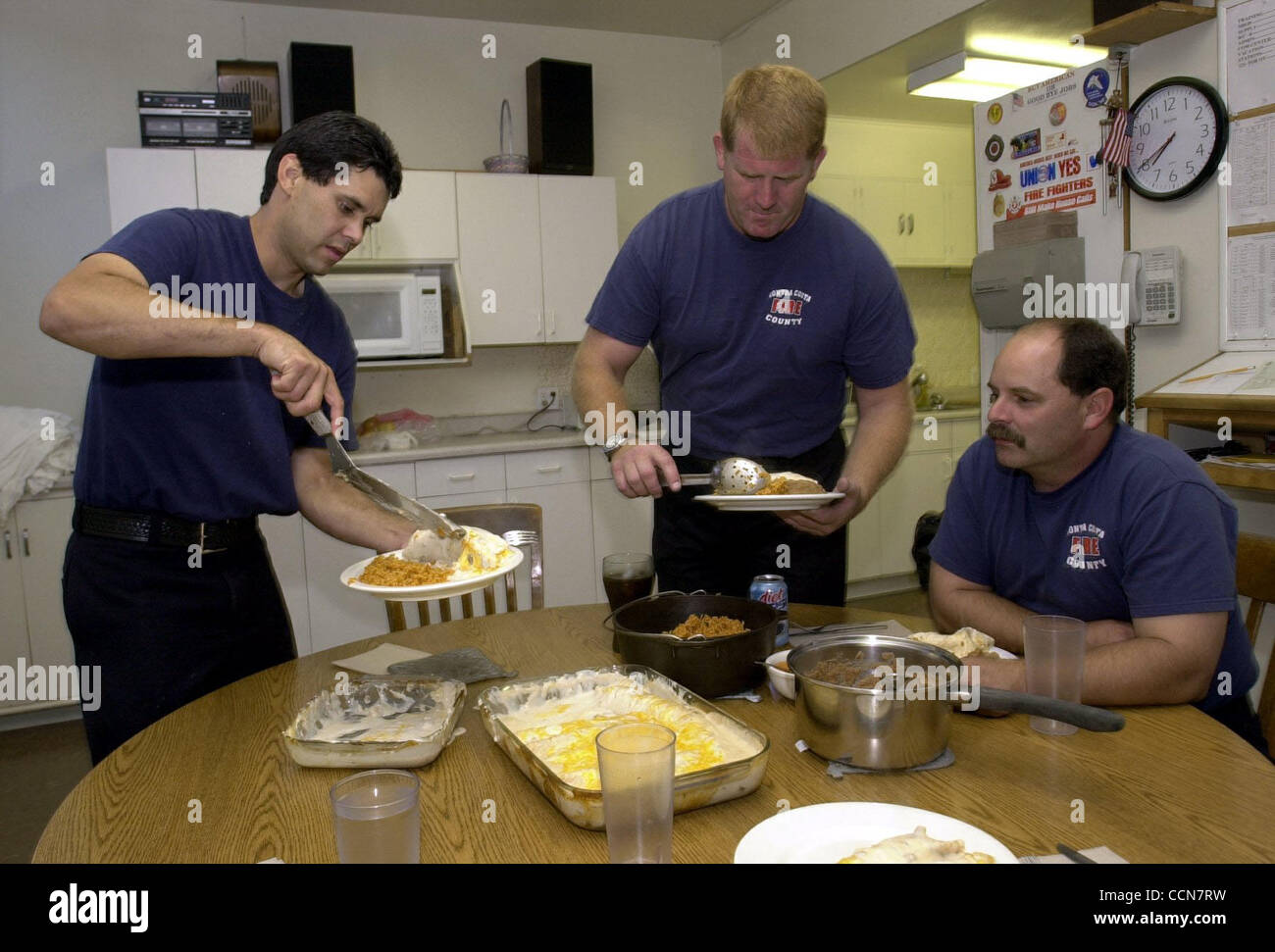 19:38 -- Capt. Eddie Gonzales, 36, left, Firefighter Tim Gleason, 41, middle, and Engineer Gary Hern, 41, right, serve themselves some chicken enchiladas, refried beans and spanish rice for the Station 81 dinner in Antioch, Calif., on Thursday August 19, 2004. (CONTRA COSTA TIMES/EDDIE LEDESMA) Stock Photo