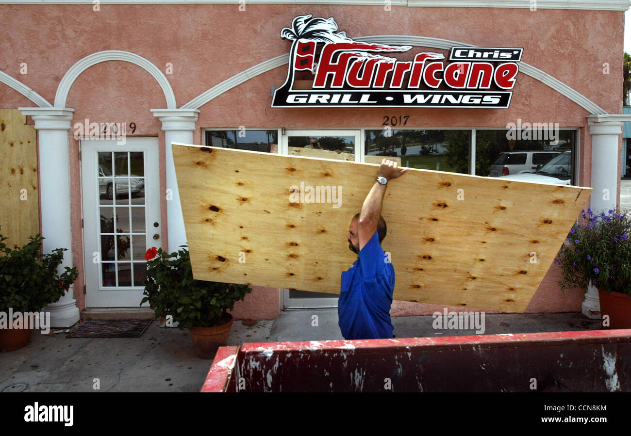 090104 TC MET Ft. Pierce...On North Hutchinson Island a stone's throw from North Beach, William Beurrier (cq) carries a piece of plywood past a restaurant featuring a hurricane as part of its' logo.  Beurrier and Chad Wouters and Keith Dean (all cq) were boarding up the building in preparation for h Stock Photo