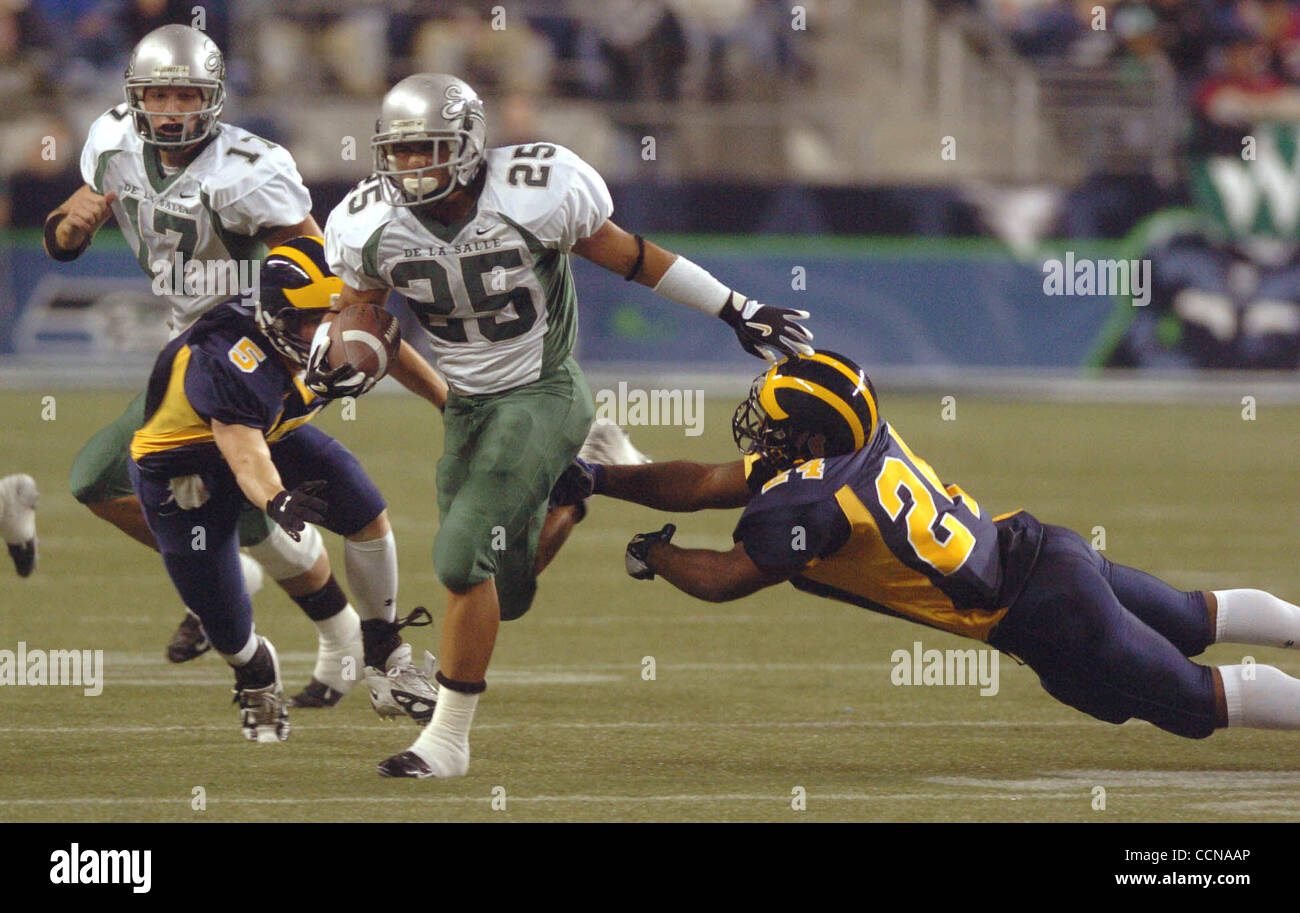 De La Salle Eduardo Lopez finds a hole and goes 45 yards for a first quarter touchdown as Bellevue Wolverines Eric Block, left and JR Hasty try to make the tackle during the 2004 Emerald City Kickoff Classic in Seattle Washington Saturday September 4,2004.(Contra Costa Times/Bob Larson) Stock Photo