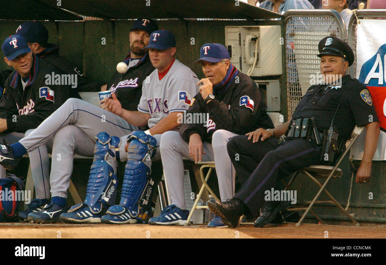 An Oakland police officer sits with the Texas Rangers bullpen during