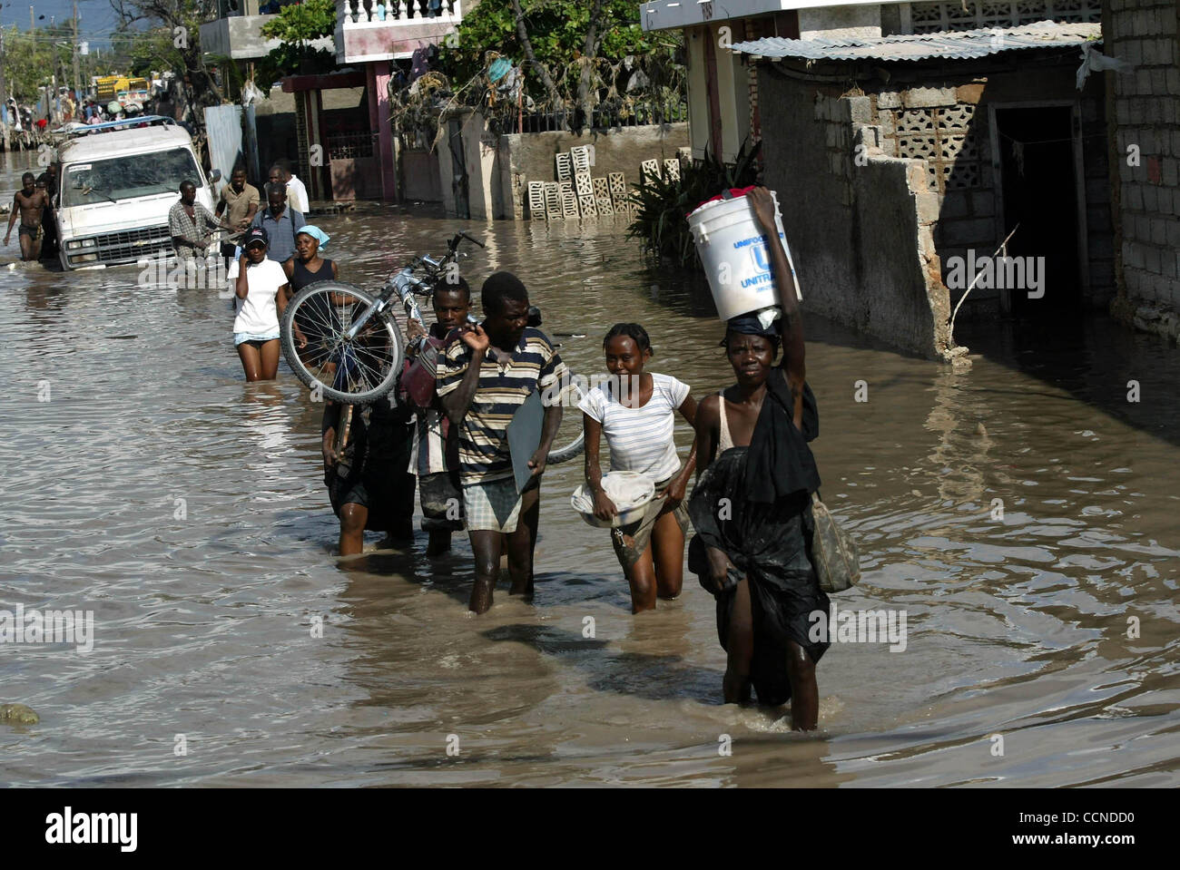 GONAIVES, HAITI; 9/22/04 Haitians carry belongings and pull a vehicle