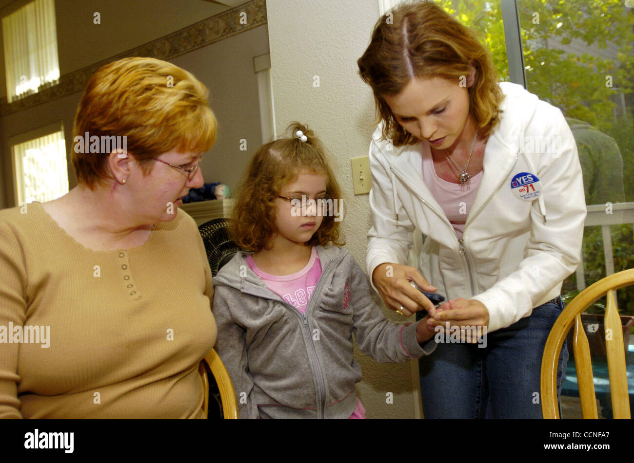 Caron Gaydon of San Ramon Calif.,right, and Jeanette Lindner of Martinez Calif., left, both have kids with diabetes and  supports stem cell research and Prop. 71. Pictured is Gaydon checking her daughter, Taylor Gaydon, blood sugar Tuesday morning Oct. 5, 2004. The states bold measure to pump $3 bil Stock Photo
