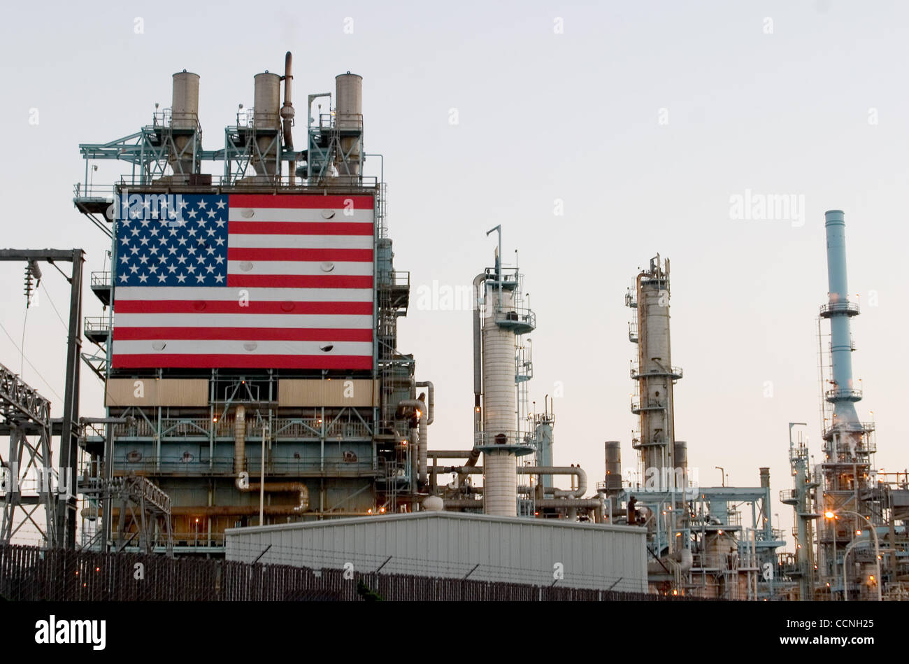 Oct 18, 2004; Long Beach, CA, USA; The Conoco philips Oil Refinery at Carson nr Long Beach California with large stars and stripes USA flag hanging next to the huge chimmney smokestacks. The refinery has security fence with barbed razor wire around it. Security has been increased at refinerys across Stock Photo