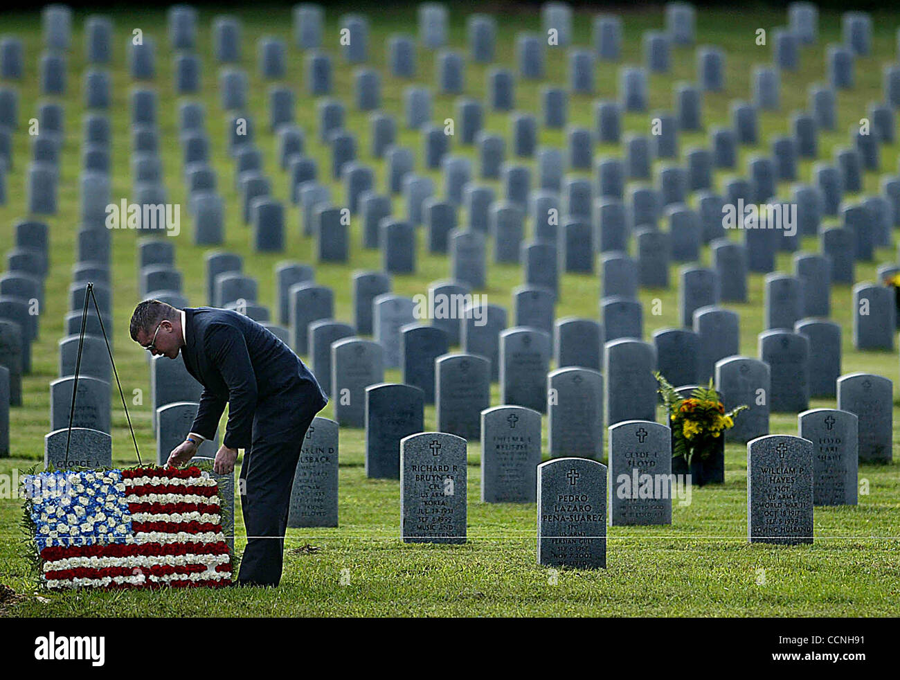 BUSHNELL - After almost everyone had gone home following the funeral of Marine Lt. Michael Felsberg at the Florida National Cemetery in Bushnell, FL, 2nd Lt. Brian Sargent of Miami bends over to adjust the wreath made of flowers that had been placed at his grave.  Sargent graduated from FIU with Fel Stock Photo