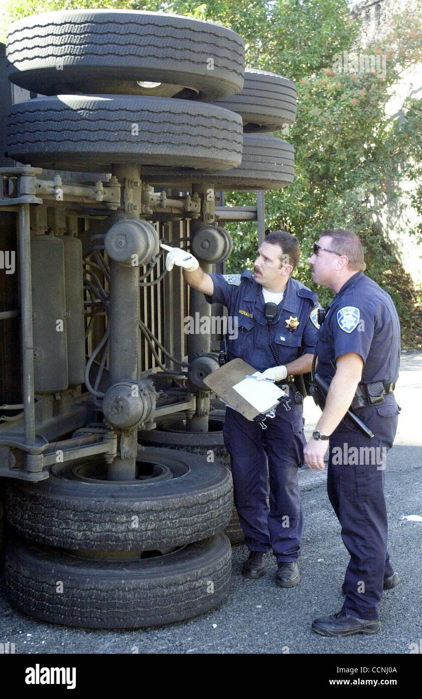 CHP officer Sergio Morales, left, and Antioch officer Joe Zanarini study the brakes this express-mail tractor trailer where the driver was killed when he crashed the truck into the G  street over crossing on east bound Highway 4 in  Antioch Calif., on Thursday Oct. 21, 2004. Morales says he was chec Stock Photo