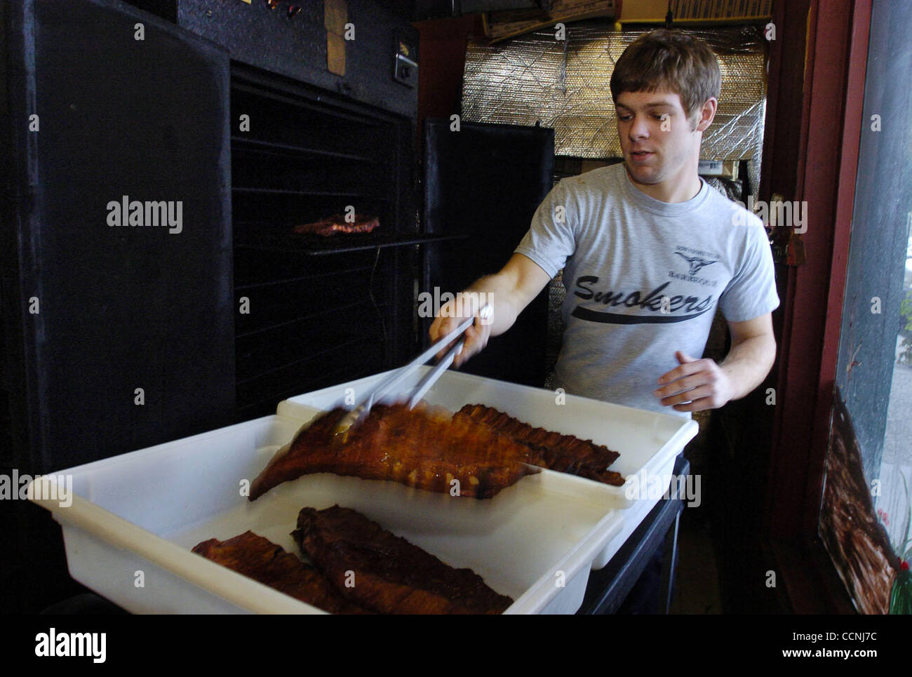 Kevin Sloan, age 18, from Brentwood, takes a rack of pork ribs out of the smoker on Sunday, October 24, 2004 at Down Home Texas Barbecue in Brentwood, Calif. Down Home Texas Barbecue will be closing their doors on October 31. Owners Vicki and Jeff Lohmann support Liberty High School by hiring the st Stock Photo