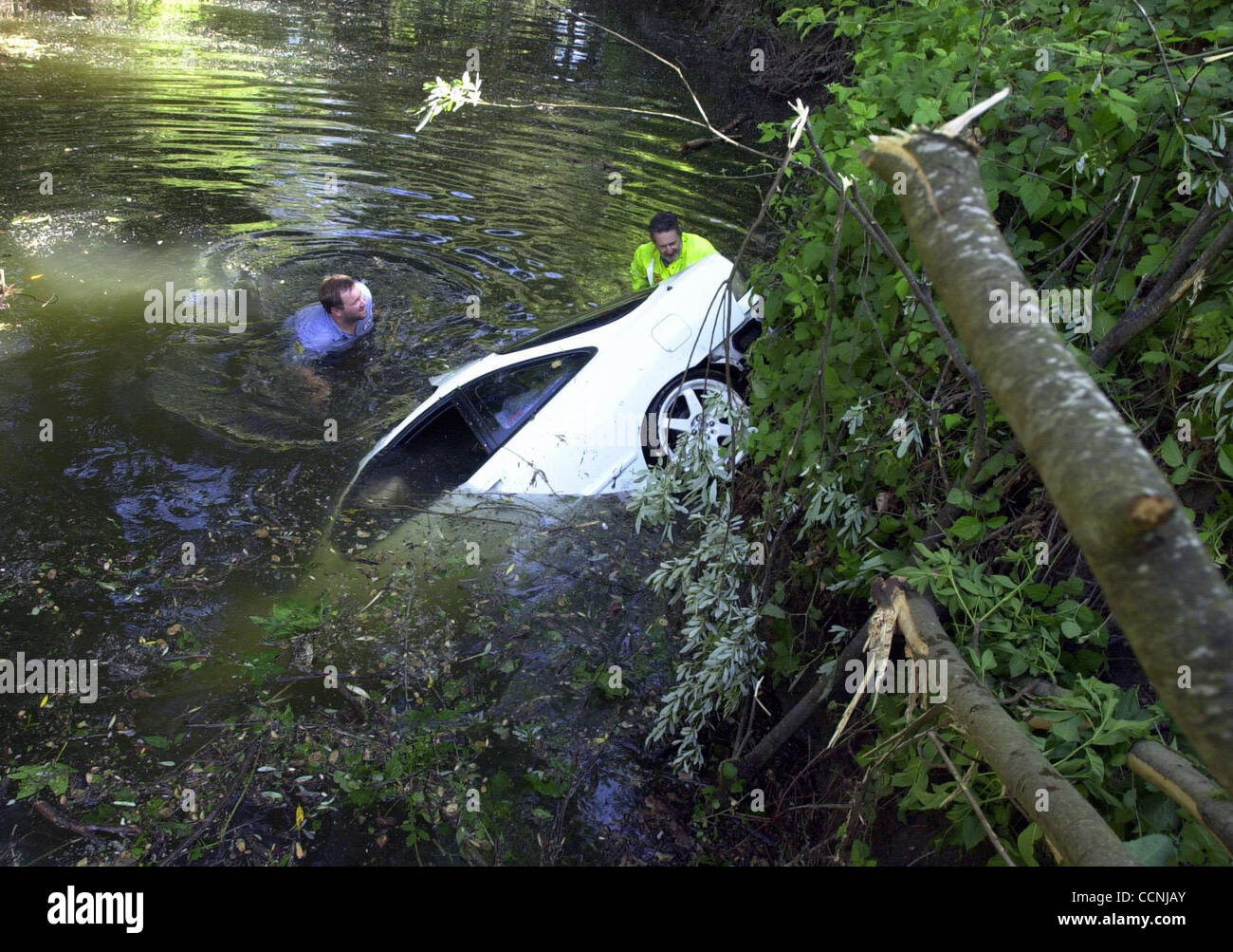 Eric Westlund, left, and James Nelmes from Lamorinda Tow go into a creek to attach cables to a car that went into a creek in Moraga, Calif. Friday, May 14, 2004. (Contra Costa Newspapers /Kristopher Skinner) Stock Photo
