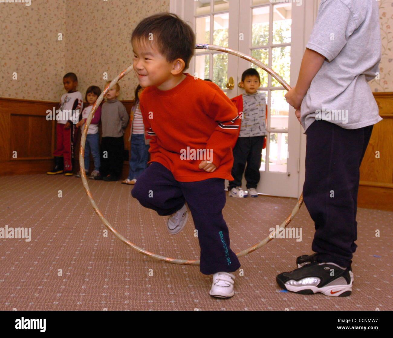 On a wet cloudy morning, Kuo Ehong, (cq) 4, of Pleasanton uses his stored up energy to run through a hula hoop during his weekly Wee Music and Dance Class taught by Debra Knox at the Century House, Tuesday, October 26, 2004, in Pleasanton, Calif.  (Contra Costa Times/Susan Tripp Pollard) Stock Photo