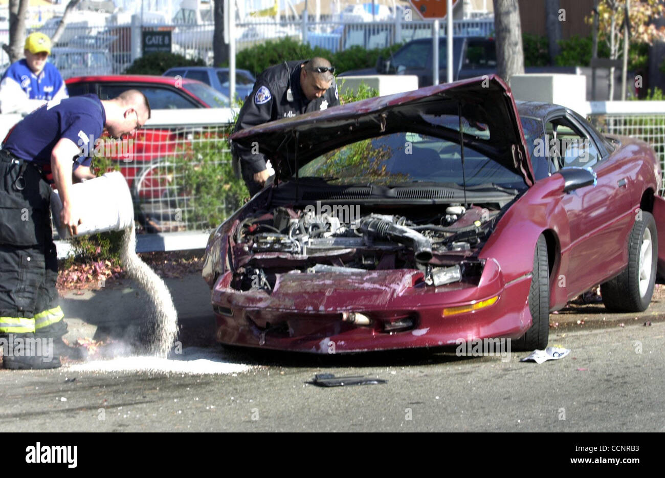 An Alameda police officer investigates the scene as a Alameda fireman