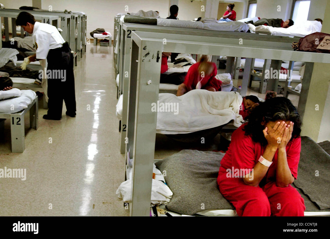 Apr. 16, 2004 - Florence, ARIZONA, USA - A female detanee sits on her cot in a women's pod at a detention facility in Forence, Az. Criminal alien detainees wear red jumpsuits. (Credit Image: © Mary F. Calvert/ZUMApress.com) Stock Photo