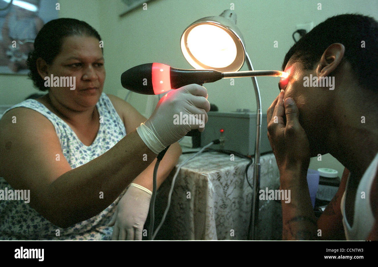 Volunteer nurse Gloria Torres (left) uses infrared to burn a tattoo off 23-year-old Christian Antunez's forehead at the Goodbye Tatto clinic in San Pedro Sula, Honduras. Antunez joined the Mara Salvatrucha 13 gang when he was 14 years old and received more than 20 treatments to remove gang tattoo fr Stock Photo
