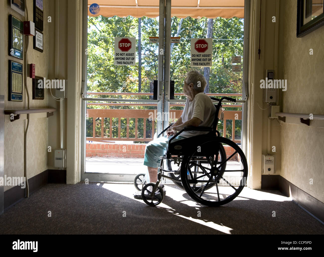 Oct. 22, 2010 - Canton, GA, USA - Patient in a wheelchair gazes out secured door of a nursing home.  The cost of receiving long-term care services at home is increasing, but not nearly as rapidly as the cost of nursing home or assisted living services, according to recent survey findings..Over the p Stock Photo