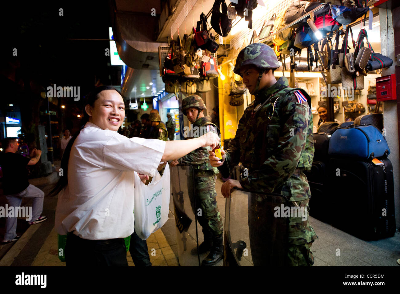 A Bangkokian gives free drinks to soldiers standing guard at Silom District in Bangkok. Security forces have been deployed to block Red Shirts protesters from advancing into the capital's financial hub. Red Shirts, also known as United Front of Democracy against Dictatorship (UDD), supporters of ous Stock Photo