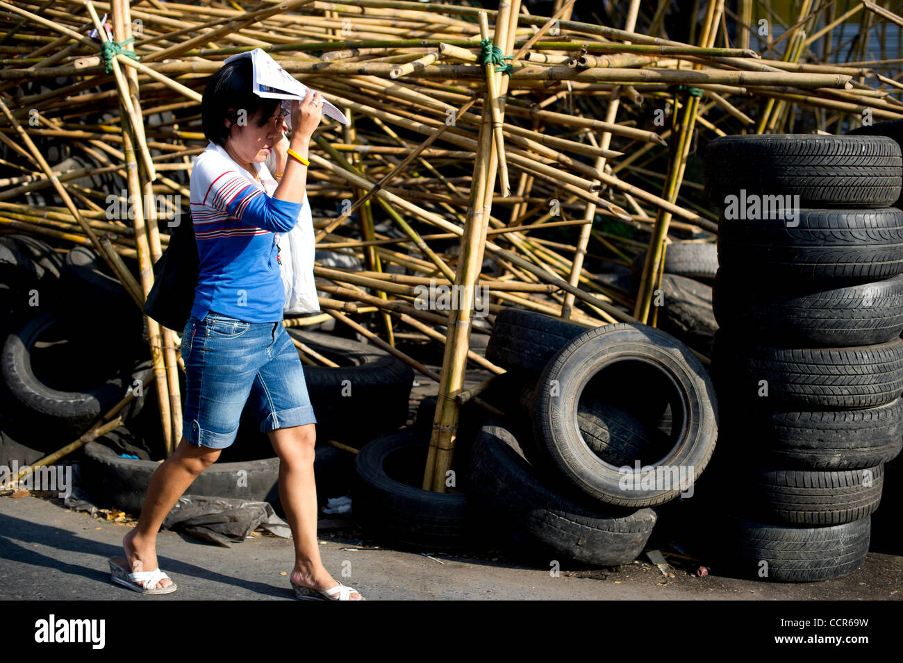 A Bangkokian walks pass barriers of tires, sharpened bamboo sticks and barb wires at an entrance to Red Shirts' fortified camp in Bangkok. Thailand security forces will surround the protest site later this evening to prevent people from joining the protest. Red Shirts, also known as United Front of  Stock Photo