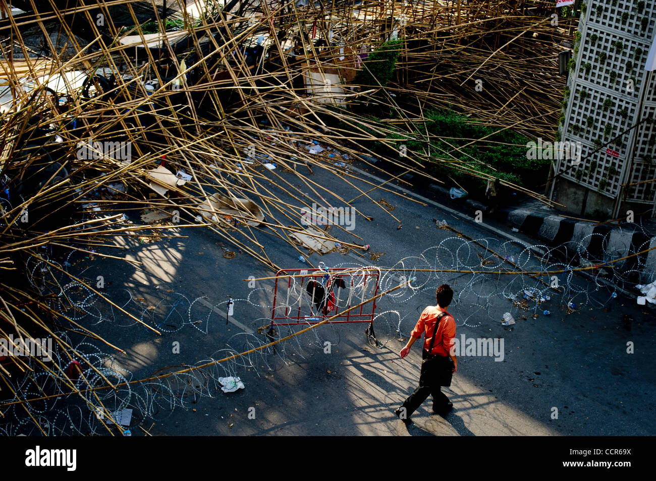 A Bangkokian walks pass barriers of tires, sharpened bamboo sticks and barb wires at an entrance to Red Shirts' fortified camp in Bangkok. Thailand security forces will surround the protest site later this evening to prevent people from joining the protest. Red Shirts, also known as United Front of  Stock Photo