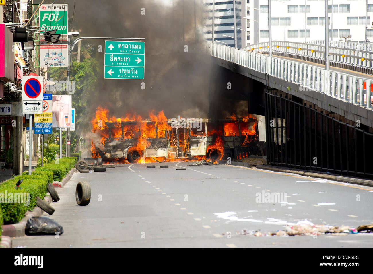 Red Shirts protesters light a bus blocking Rama IV road on fire during Thai government crack down on Red Shirts protest site at Ratchaprasong. Red Shirts leaders have now surrendered ending their prolong protest. Stock Photo