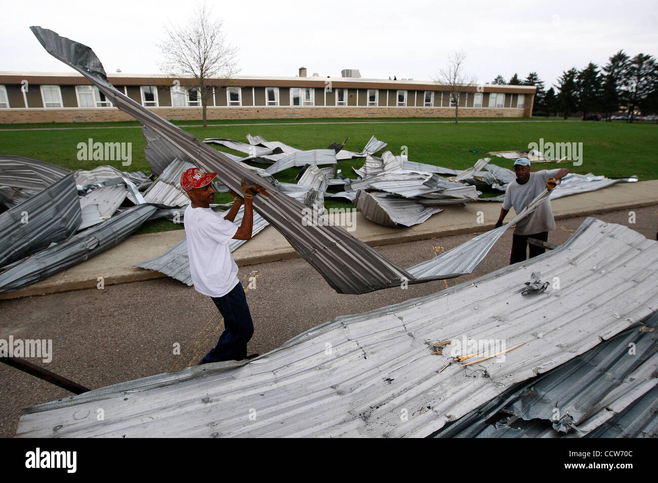 Apr 06, 2010 - Dowagiac, Michigan, USA - High winds destroyed a hanger at Dowagiac Municipal Airport. Metal roofing from the hanger was blown across M51, landing in the parking lot of Dowagiac High School. Doug Wolverton , 41, and his friend clear the metal roofing from in front of the school. At le Stock Photo