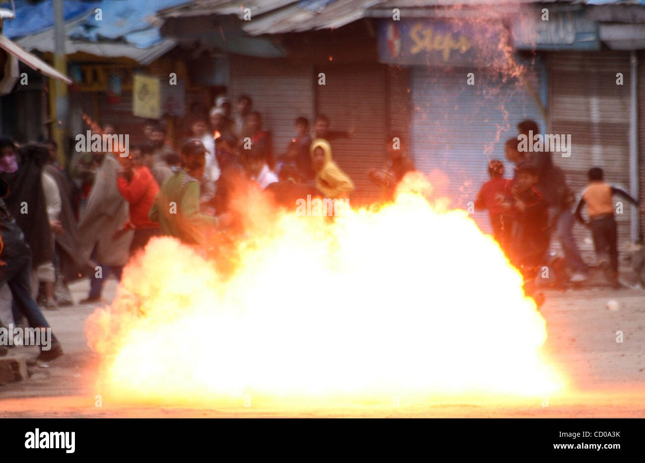 A teargas shell explodes near Kashmiri Muslim protesters during a protest in Srinagar April 11, 2008. Police in Indian Kashmir fired tear gas on Friday to disperse hundreds of demonstrators demanding an investigation into nearly a thousand unmarked graves in Kashmir discovered by a local human right Stock Photo