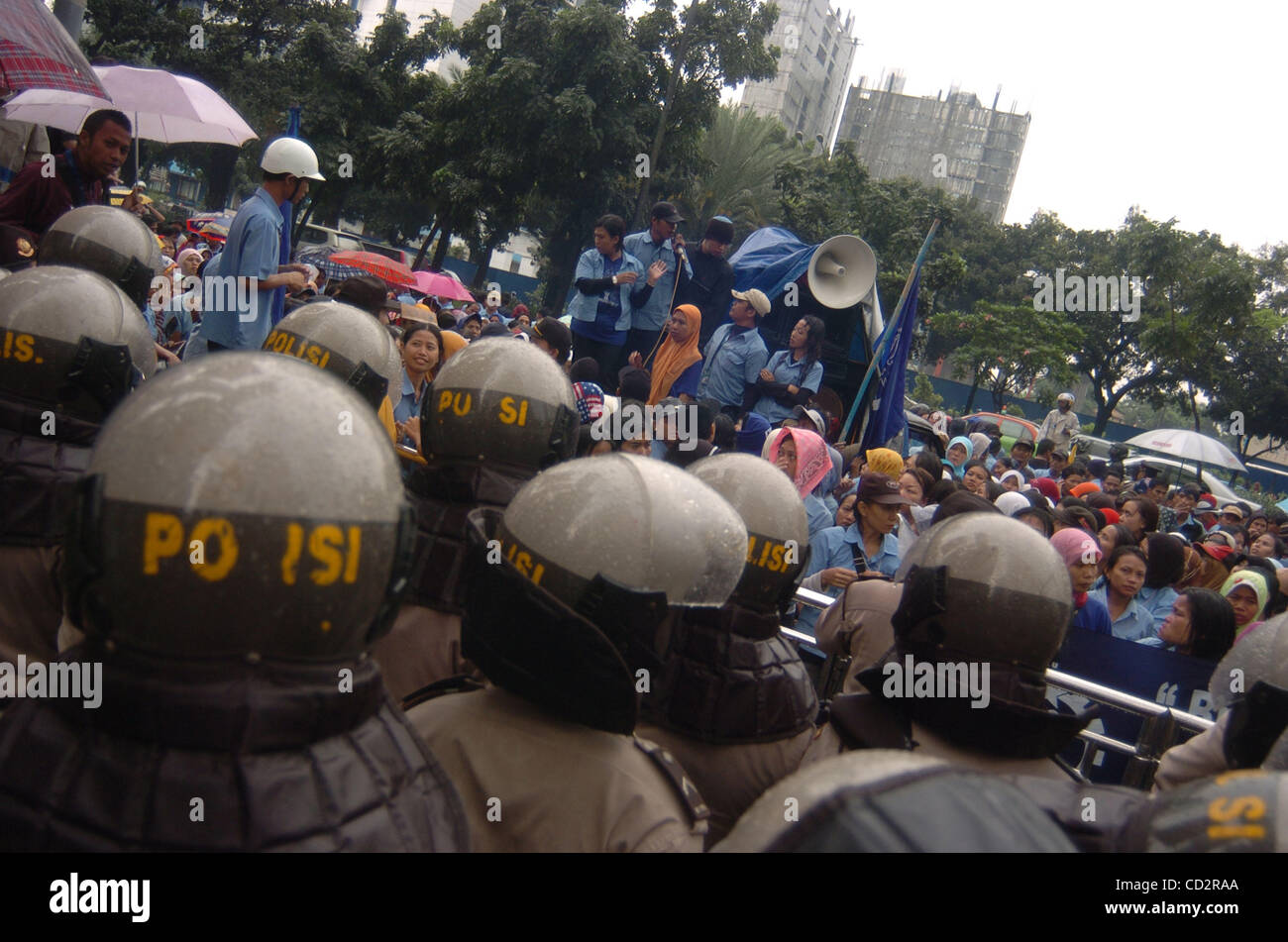 Police guards labourers of Adidas Indonesia during a protest outside of the  Adidas Indonesia office in Jakarta, March 19, 2008. Hundreds of Indonesian  labourers from Adidas's Indonesia shoe factories staged a protests