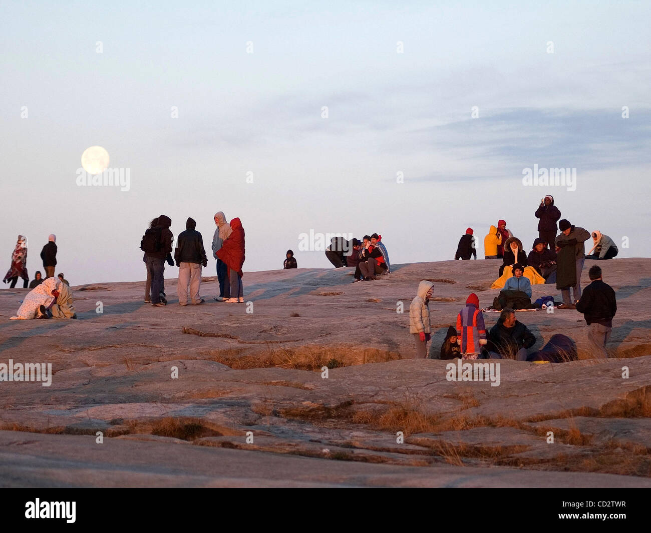 Worshipers watch as the sun rises during the Easter Sunrise Service on the top of Stone Mountain, Ga. as the moon sets behind them. The world's largest piece of exposed granite, Stone