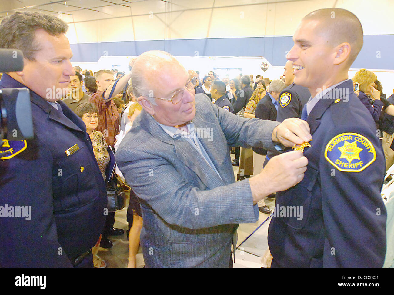 Bud Harlan, center, pins a star on his biological grandson Geoffrey Ball after Ball is sworn in as a member of the Alameda County Sheriff's Department on Friday, April 18, 2008 in a ceremony at the Alameda County Fairgrounds in Pleasanton, Calif. Ball's biological uncle Dean Stavert is at the far le Stock Photo