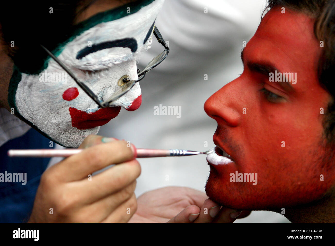 2008/08/29: Iranian young man helps his friend to color his face during ...