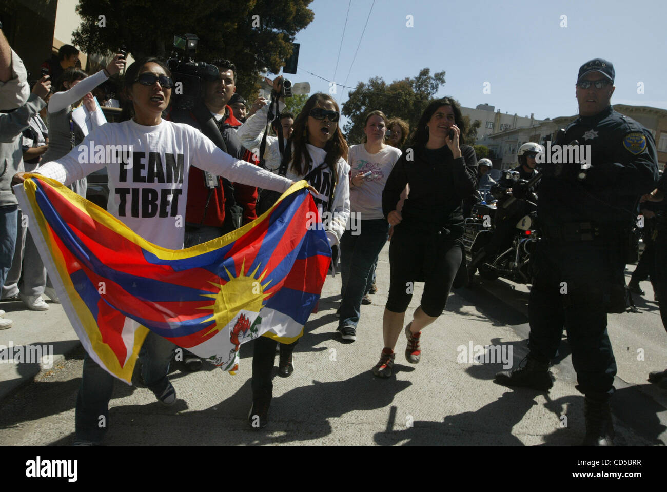 With the Olympic torch moving by them, Lob Sang (with flag) other ...