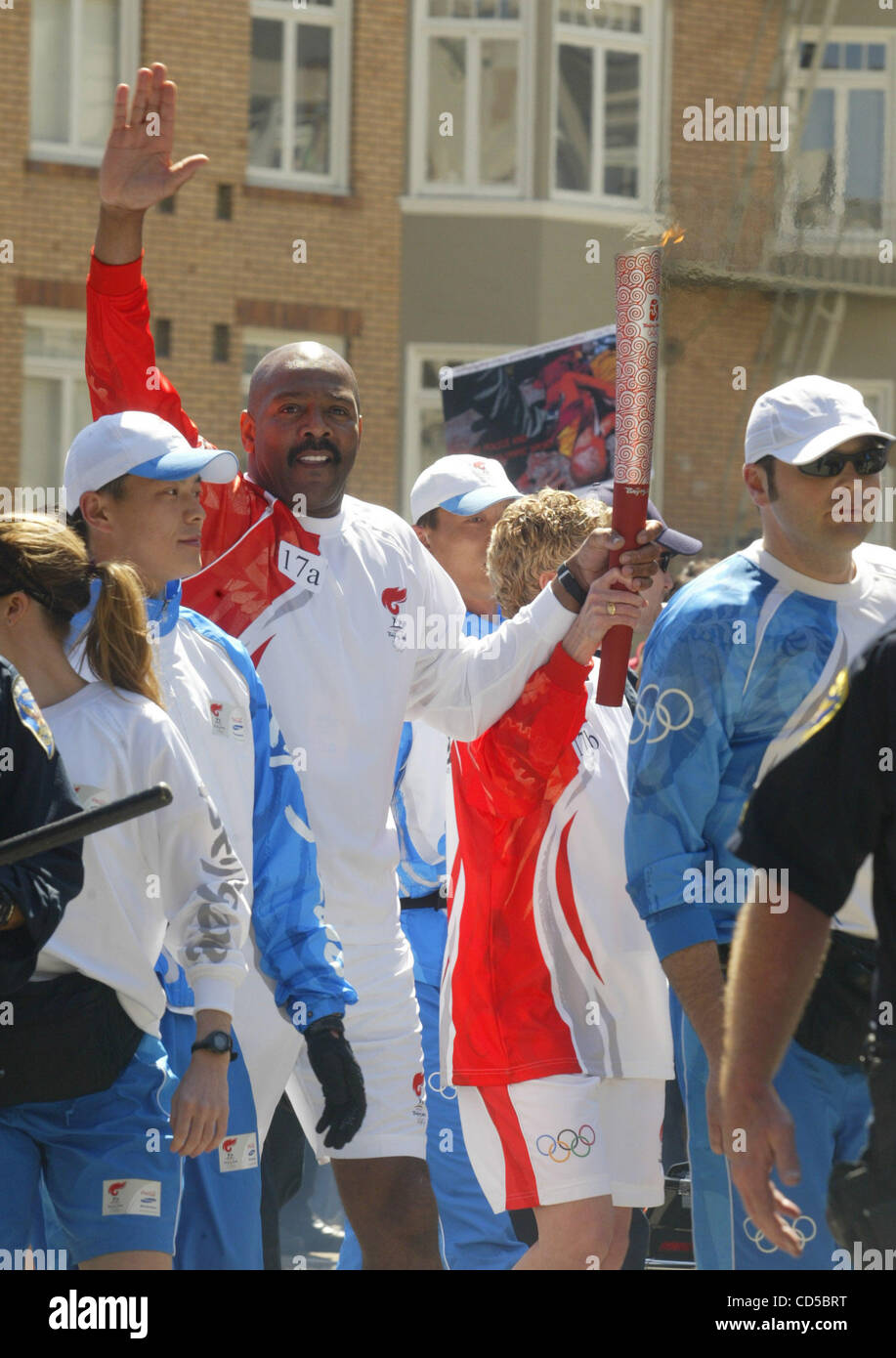 Surrounded by police, an Olympic torch bearer waves on Van Ness Ave. in ...