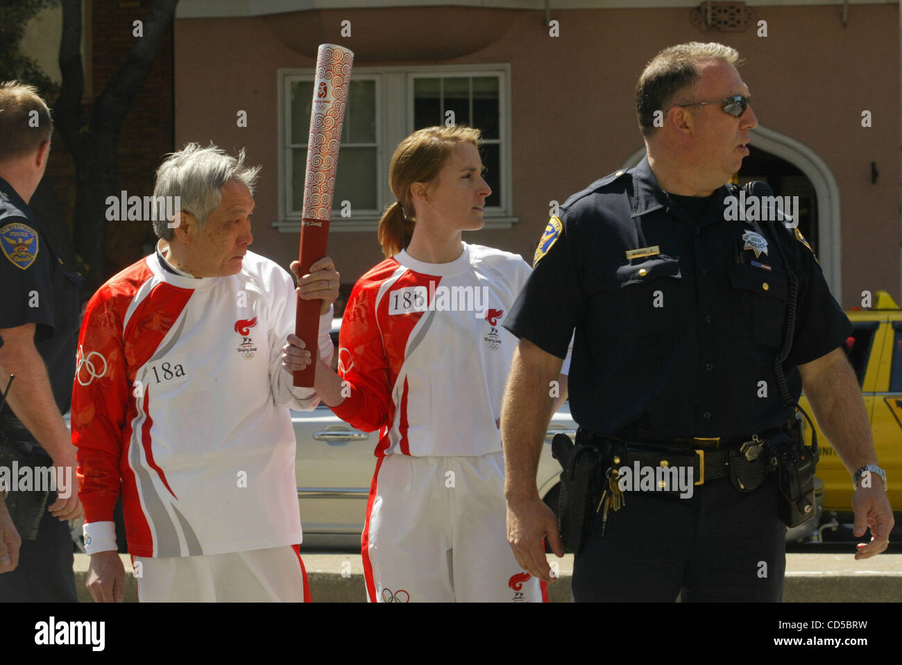 Surrounded by police, Olympic torch bearers wait for the flame pass on ...
