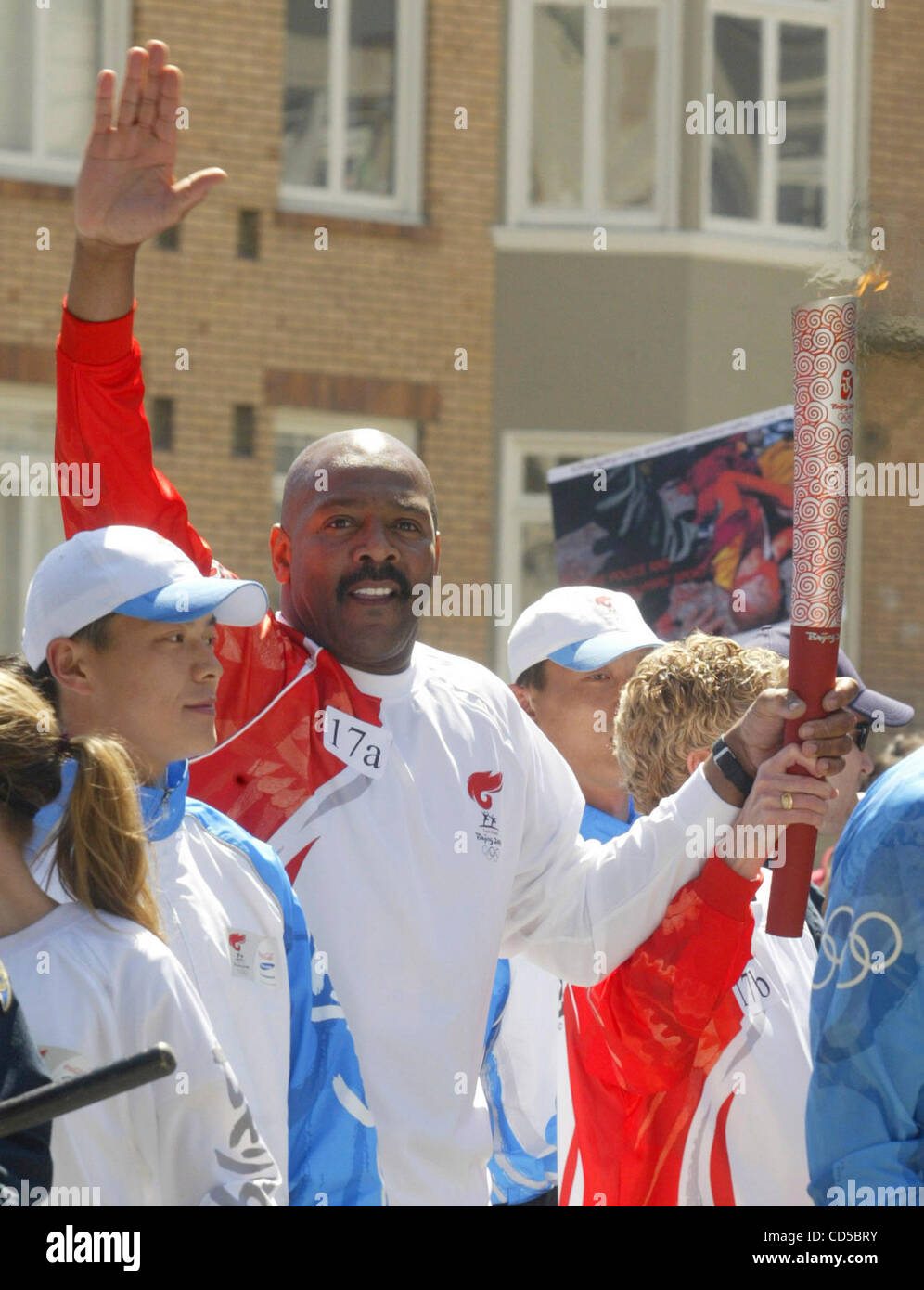 Surrounded by police, an Olympic torch bearer waves on Van Ness Ave. in ...