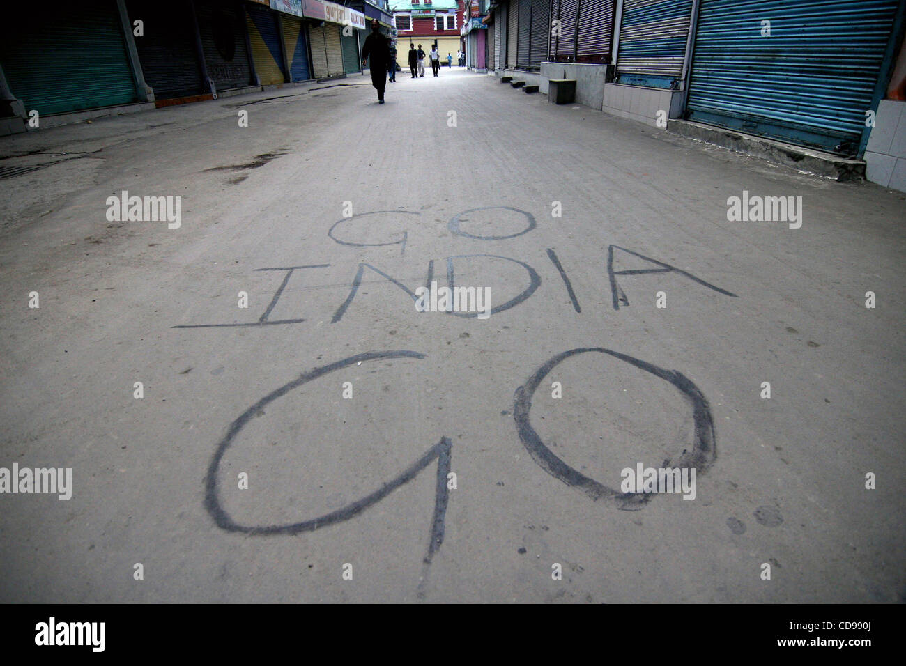 A kashmiri muslim walks past a deserted street in Srinagar, the summer capital of Indian  Kashmir, as many people on Saturday, June 26, 2010 registered their protests against 'Indian Occupation' by displaying graffiti's on roads, electric poles and walls Photo/Altaf Zargar/Zuma Press Stock Photo