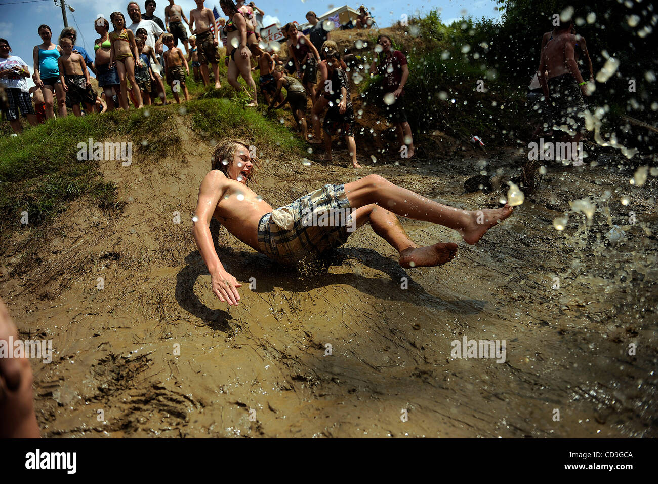 SATURDAY JULY 10, 2010 EAST DUBLIN, GEORGIA - A Redneck Games participant slides down a muddy hill into the river at Buckeye Park during the Redneck Games in East Dublin, Georgia. The games started in 1996 as spoof on the Olympics which were being held in Atlanta, Georgia at the time. participants c Stock Photo