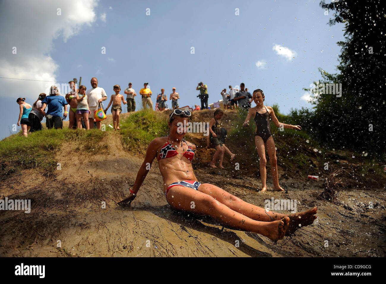 SATURDAY JULY 10, 2010 EAST DUBLIN, GEORGIA - A Redneck Games participant slides down a muddy hill into the river at Buckeye Park during the Redneck Games in East Dublin, Georgia. The games started in 1996 as spoof on the Olympics which were being held in Atlanta, Georgia at the time. participants c Stock Photo