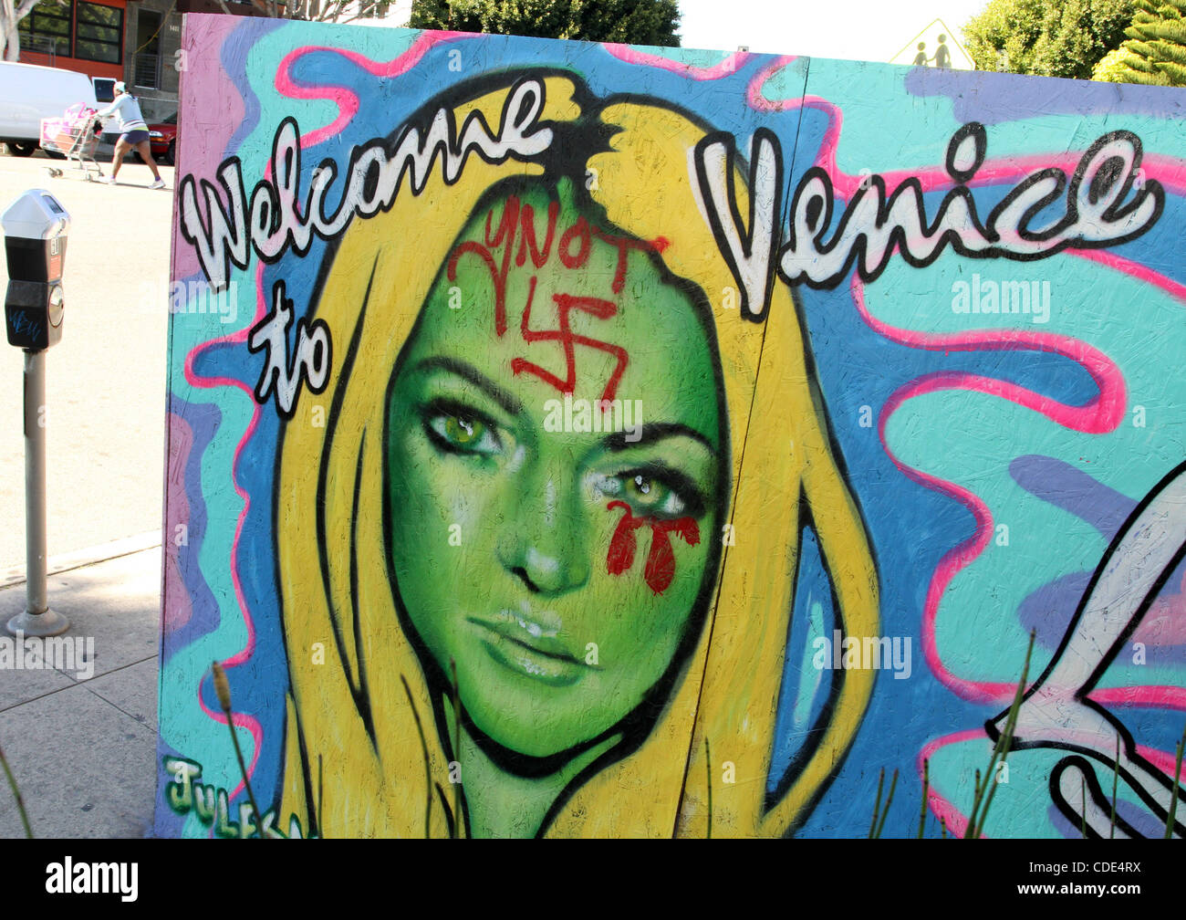 Feb. 3, 2011 - Venice, California, U.S - A man walks past Venice artist Jules MuckÃ”s Ã’Welcome to VeniceÃ“ painting of Lindsay Lohan that was defaced with a swastika on her forehead and blood red tears from her eye. Many residents of Venice Beach are unhappy that the troubled actress has recently m Stock Photo